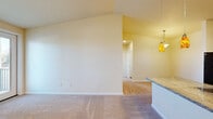 Located at 1401 Nelson Rd NE in Moses Lake, Washington, this 2-bedroom, 1-bathroom residence offers a well-organized single-floor layout designed for comfortable everyday living. The combined kitchen and living area serves as the heart of the home, where the kitchen stands out with warm wood cabinetry, granite-style countertops, black appliances including a refrigerator, range, and microwave, and a peninsula with a double stainless steel sink illuminated by distinctive amber pendant lights. The living area features plush carpeting, a front entry door, and a wall-mounted heating unit. A sliding glass door leads to a private balcony with outdoor views. Both bedrooms are carpeted and filled with natural light from blinded windows. The primary bedroom includes a mirrored sliding closet door, while the second bedroom benefits from dual windows and a wall-mounted HVAC unit. The full bathroom is finished with wood-look flooring, a granite-topped vanity with wood cabinetry, a full soaking tub with shower, and convenient access to the in-unit laundry closet, which houses a full-size washer and dryer. A dedicated hallway connects all spaces, contributing to a cohesive and functional floor plan throughout.