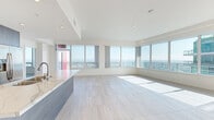 Located in San Diego's vibrant East Village neighborhood, this high-rise unit offers a bright, contemporary living experience defined by clean lines and an abundance of natural light. The open-concept main living area is anchored by floor-to-ceiling windows that frame sweeping panoramic views of the San Diego skyline, bay, and surrounding cityscape, while a private balcony extends the living space outdoors. Light-toned tile flooring flows seamlessly throughout, enhancing the airy, modern aesthetic.

The sleek kitchen features a large central island with a quartz countertop, dark wood cabinetry, subway tile backsplash, stainless steel appliances including a refrigerator with ice maker, and recessed lighting overhead. The bedrooms are generously proportioned, bathed in natural light, and include sliding mirrored closet doors and private balcony access. A spacious walk-in closet with multi-level chrome shelving and hanging rods provides ample storage. The bathrooms are finished with crisp white vanities, quartz countertops, polished chrome fixtures, and a soaking tub surrounded by dramatic marble-look tile. Every detail reflects a refined, move-in-ready standard of urban living.
