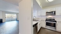 This single-floor residence in Walnut Creek, California offers a thoughtfully designed layout with a clean, modern aesthetic throughout. The kitchen is a standout feature, showcasing white shaker cabinetry, white subway tile backsplash, light countertops, and a full suite of stainless steel appliances including a gas range, microwave, dishwasher, and refrigerator. Dark wood-style flooring runs through the kitchen and connects seamlessly to the open living and dining area, which is bathed in natural light from a large sliding glass door leading to an outdoor space. A fireplace anchors the living room, adding warmth and character to the expansive, open area. Both bedrooms are carpeted and feature mirrored sliding closet doors, offering ample storage and a sense of added space. Two full bathrooms mirror each other in design, each finished with white vanity cabinetry, wood-style flooring, and a tub-shower combination enclosed by sliding glass doors. The overall interior palette of crisp whites and neutral tones creates a bright, cohesive atmosphere well-suited to everyday living.