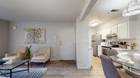 This single-floor residence offers a thoughtfully organized layout that balances comfort and functionality throughout its interconnected spaces. The entryway welcomes residents with light gray walls, wood-look flooring, and a clean, modern aesthetic that carries consistently through the entire unit.

The living area serves as the central hub of the space, featuring a sliding glass door that opens to an outdoor patio, allowing natural light to fill the room and providing a seamless indoor-outdoor connection. Adjacent to the living area, a dedicated dining nook is highlighted by a pendant light fixture and sits in close proximity to the galley-style kitchen, which is outfitted with white cabinetry, light speckled countertops, a stainless steel refrigerator, and a stainless electric range with oven.

The two bedrooms share a similar design language, each featuring wood-look flooring, neutral walls, multiple windows with blinds that admit ample natural light, and individual closets offering practical storage. The bathroom includes a wide vanity with speckled countertops, white cabinetry, built-in shelving, and a large mirror, contributing to a bright and functional space. Throughout, the unit maintains a cohesive, contemporary character.