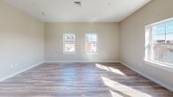 Located at 186 Main St in Auburn, Maine, this thoughtfully designed single-floor unit offers a clean, contemporary aesthetic throughout. The open-concept layout seamlessly connects the kitchen and living area, creating a bright and functional space ideal for everyday living. Wide-plank wood-style flooring runs continuously throughout, lending warmth and visual cohesion to the entire unit.

The kitchen is well-appointed with crisp white shaker cabinets, light countertops, and a full suite of stainless steel appliances, including a range, over-the-range microwave, refrigerator, and dishwasher. A single-basin sink with a modern faucet completes the functional workspace.

The living area is generously proportioned and filled with natural light, courtesy of multiple white-framed windows and a sliding glass door that opens to an outdoor balcony. Views of the surrounding Auburn cityscape add to the appeal, offering a connection to the vibrant downtown environment.

The bathroom features wood-style flooring consistent with the rest of the unit, a white vanity with a marble-style countertop, and clean neutral wall tones. The overall palette across the space — soft beige walls, white trim, and light flooring — creates a calm, airy ambiance that feels both modern and inviting.