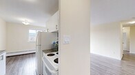 Located at 53 McMurchy Ave N in Brampton, Ontario, this two-bedroom, one-bathroom unit offers a well-organized layout across a single floor. Light grey laminate flooring runs throughout the space, providing a clean and cohesive look that complements the neutral cream-toned walls and white trim.

The living room is a generous open area filled with natural light from a large sliding glass door that leads directly to a private balcony. The balcony offers elevated views of the surrounding greenery, neighbouring buildings, and the broader Brampton skyline — an appealing outdoor extension of the living space.

The galley-style kitchen features white cabinetry with modern bar-pull hardware, dark countertops, a tiled backsplash, and full-sized appliances including a refrigerator and stove. The efficient layout maximizes storage and counter space.

Both bedrooms are well-proportioned with the same laminate flooring and neutral walls. The primary bedroom includes a window with city views and a baseboard heating unit, while the second bedroom features a built-in sliding door closet. Each room offers a calm, versatile space suitable for various configurations.

The bathroom is finished with white tile flooring, a soaker tub with overhead shower, a toilet, and a vanity with a dark granite-style countertop and modern cabinetry.