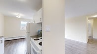 Located at 53 McMurchy Ave N in Brampton, Ontario, this two-bedroom, one-bathroom unit offers a well-organized layout across a single floor. Light grey laminate flooring runs throughout the space, providing a clean and cohesive look that complements the neutral cream-toned walls and white trim.

The living room is a generous open area filled with natural light from a large sliding glass door that leads directly to a private balcony. The balcony offers elevated views of the surrounding greenery, neighbouring buildings, and the broader Brampton skyline — an appealing outdoor extension of the living space.

The galley-style kitchen features white cabinetry with modern bar-pull hardware, dark countertops, a tiled backsplash, and full-sized appliances including a refrigerator and stove. The efficient layout maximizes storage and counter space.

Both bedrooms are well-proportioned with the same laminate flooring and neutral walls. The primary bedroom includes a window with city views and a baseboard heating unit, while the second bedroom features a built-in sliding door closet. Each room offers a calm, versatile space suitable for various configurations.

The bathroom is finished with white tile flooring, a soaker tub with overhead shower, a toilet, and a vanity with a dark granite-style countertop and modern cabinetry.