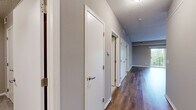 Located at 637 Main St NW in Elk River, Minnesota, this two-bedroom, one-bathroom single-floor residence offers a well-designed layout with a comfortable and modern feel throughout. The open-concept kitchen and living area serves as the heart of the home, featuring rich hardwood-style flooring, dark navy cabinetry extending to the ceiling, light stone countertops, stainless steel appliances including a range, microwave, and refrigerator, and a central island with pendant lighting. The living room is bright and airy, enhanced by sliding glass doors that open onto a private balcony overlooking lush, mature trees — bringing the outdoors in with natural light and scenic views. Both bedrooms are carpeted for comfort and finished in neutral tones. The primary bedroom includes a double-door closet and benefits from a tray ceiling detail and a window with greenery views. The second bedroom is cozy and versatile with plush carpet and a textured ceiling. The bathroom is clean and functional, featuring a full tub-shower surround. Throughout the space, consistent warm-gray paint tones, white trim, and thoughtful finishes create a cohesive and inviting atmosphere.