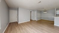 Located at 1861 Stella Ln in Fort Walton Beach, Florida, this 2-bedroom, 2-bathroom single-story home offers a clean, neutral aesthetic throughout. Light wood-style flooring runs seamlessly across the living spaces, complementing the soft gray walls and crisp white trim found in every room.

The open living area welcomes natural light through a glass-paneled exterior door and adjacent window, creating a bright and airy atmosphere. A chandelier accent adds a touch of elegance to the dining area. The galley-style kitchen is efficiently laid out with white cabinetry, white appliances including a range, microwave, refrigerator, and dishwasher, along with a stainless steel sink and ample counter space.

Both bedrooms feature ceiling fans with light fixtures and continue the wood-style flooring. The primary bedroom includes a dedicated walk-in closet with built-in shelving, offering practical storage. The second bedroom benefits from dual windows, filling the room with natural light. Each bathroom is equipped with a tub-shower combination and wood-style flooring, maintaining the home's cohesive design. Two closets provide additional storage throughout the home. Textured ceilings are present throughout, adding a classic residential character to the space.
