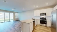 Located at 14153 Wind Row Dr in Jacksonville, FL, this two-story home offers four bedrooms, three bathrooms, and a thoughtfully designed layout spread across two floors. The ground floor sets a welcoming tone with an open-concept kitchen and living area. The kitchen is a standout, featuring crisp white shaker cabinetry, light granite countertops, a central island with a sink, subway tile backsplash, and a full suite of stainless steel appliances. Light wood-look flooring flows throughout the main level, complementing the neutral color palette. Sliding glass doors in the living area invite natural light and provide direct access to the backyard. The attached garage offers ample storage space and includes a water heater and electrical panel. Upstairs, the larger floor plan houses all four bedrooms, each finished with plush carpet, neutral walls, and window blinds that allow for natural light. The generously sized primary bedroom comes with its own closet. Three bathrooms serve the home, including one with a walk-in shower and wood-look tile flooring. A hallway and four closets ensure practical storage throughout. This home combines clean, modern finishes with functional design for comfortable everyday living.
