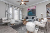 Located in the Princeton Lakes community of Southwest Atlanta, this single-floor residence offers a thoughtfully designed layout with a seamless flow between living, dining, and kitchen spaces. The kitchen is a standout feature, showcasing rich cherry wood cabinetry, granite countertops, a green glass tile backsplash, stainless steel appliances, and pendant lighting over a central island — all framed by crown molding that adds a refined architectural touch. The open living and dining area benefits from large French doors that invite natural light and feature crown molding, ceiling fans, and wood-style flooring. The dining space is further accentuated by arched architectural details and decorative wainscoting. The bedrooms are carpeted for comfort, each equipped with ceiling fans and ample natural light through slatted blinds. One bedroom includes a spacious walk-in closet with built-in shelving. The bathrooms are well-finished, with granite vanity countertops, wood-style flooring, and tiled tub-shower combinations with mosaic accent detailing. Together, the spaces create a cohesive, comfortable living environment with consistent attention to quality finishes throughout.