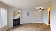 This efficiently designed one-bedroom, one-bathroom residence offers a practical and comfortable layout across a single floor, encompassing five distinct rooms: a living room, bedroom, kitchen, bathroom, and hallway. The living room serves as the heart of the home, showcasing light hardwood-style flooring, a ceiling fan with integrated lighting, and a standout wood-burning fireplace with a classic white mantle, brick hearth, and an oversized mirror accent above — adding depth and brightness to the space. A large window with vertical blinds invites natural light throughout. The kitchen features warm wood cabinetry, granite-look countertops, a stainless steel sink, a dishwasher, and a full-size refrigerator, all set atop matching hardwood-style flooring. The bedroom is finished with plush carpeting, a ceiling fan, a natural light window with vertical blinds, and mirrored sliding closet doors that enhance the sense of space. The bathroom includes a full tub-shower combo, a granite-top vanity with wood cabinetry, and hardwood-style flooring. A hallway connects the rooms and features a built-in linen closet with multiple shelves, offering practical storage within the compact footprint.