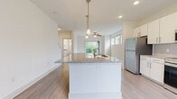 Located at 11310 Vandelay Court in Charlotte, NC, this well-appointed three-story home offers a thoughtfully designed layout with quality finishes across every level. The open-concept main living area centers around a striking kitchen island topped with granite countertops and an integrated sink, illuminated by elegant pendant lighting. White shaker cabinetry, stainless steel appliances — including a refrigerator, range, and microwave — and warm wood-look flooring complete the kitchen's clean, contemporary aesthetic. The living and dining areas flow seamlessly from the kitchen, with a ceiling fan overhead and sliding glass doors that invite natural light and outdoor views.

The bedrooms are carpeted for comfort and feature multiple windows that frame lush tree-lined views, along with ceiling fans to enhance airflow. The primary bathroom is well-equipped with a granite-topped double vanity with brushed gold hardware, a glass-enclosed shower, and access to a walk-in closet. A secondary bathroom offers a tub-shower combination and matching wood-look flooring. A dedicated laundry area houses a full-size washer and water heater. Throughout the home, a neutral color palette, recessed lighting, and consistent use of quality materials create a bright, cohesive, and move-in-ready living environment.
