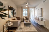 Located in Jurupa Valley, CA, this well-appointed single-floor residence offers a thoughtfully designed layout combining modern aesthetics with everyday functionality. The interior entry features warm wood-look flooring and curated abstract artwork, setting a contemporary tone throughout.

The kitchen is a standout space, showcasing sleek dark gray cabinetry, white quartz countertops, a classic subway tile backsplash, stainless steel appliances, and a kitchen island with bar seating — ideal for both cooking and casual dining.

The living room offers a welcoming atmosphere with wood-look flooring, a ceiling fan, natural light through shuttered windows, and tasteful wall art that adds character to the space.

Two bedrooms provide comfortable retreats, each outfitted with plush carpeting, ceiling fans, and windows dressed with sheer curtains and blinds that allow ample natural light. The full bathroom is clean and modern, featuring dark cabinetry, a white countertop vanity, a large mirror, and a shower-tub combination.

A private balcony with a charming arched opening frames views of the surrounding community, offering a serene outdoor sitting area. The attached garage provides convenient, enclosed parking and additional storage space.