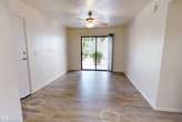 This 690-square-foot, single-story apartment at 2601 E McKellips Rd in Mesa, Arizona offers a practical and well-appointed 2-bedroom, 2-bathroom layout. Wood-look plank flooring runs throughout the unit, providing a cohesive and easy-to-maintain finish. Each bedroom is equipped with a ceiling fan and includes a built-in closet with shelving; the primary bedroom spans 120 square feet and features direct access to its own bathroom. The second bedroom also benefits from natural light via a vertical window with outdoor views. Both bathrooms are finished with granite-style countertops, cream cabinetry with brushed nickel hardware, and undermount sinks. One bathroom features a full tub/shower combo. The kitchen is efficiently designed in a galley style, outfitted with cream cabinetry, granite-style countertops, black appliances including an electric range and refrigerator, and a skylight overhead that brings in additional natural light. A connecting hallway links all rooms seamlessly. The unit's neutral color palette and clean finishes create a bright, functional living environment suited for a variety of lifestyles.