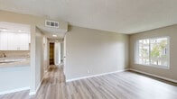 Located at 7731 Trask Ave in Westminster, California, this single-floor unit offers a thoughtfully updated interior with a clean, neutral aesthetic throughout. Light-toned luxury vinyl plank flooring runs continuously across all rooms, contributing to a cohesive and modern feel.

The living area is generously sized, featuring a ceiling fan, textured ceiling, and a large window with vertical blinds that invite natural light and views of surrounding palm trees and greenery. An entry door with an adjacent window further brightens the space.

The kitchen stands out with white shaker-style cabinetry, granite-look countertops, a stainless steel gas range with an overhead ventilation hood, and ample upper and lower cabinet storage — making it both functional and visually refined.

The bedrooms are well-proportioned, each featuring textured ceilings, neutral warm-toned walls, and windows that frame outdoor views. Ceiling fans are present in multiple rooms for added comfort. A spacious walk-in closet with built-in multi-tier shelving and hanging rods provides extensive storage.

The bathroom is finished with white cabinetry, a granite-look vanity countertop, a framed mirror, and a full shower-tub combination with chrome fixtures. The overall design palette — neutral walls, white trim, and consistent flooring — creates a bright, move-in-ready environment.