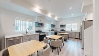 Located at 1360 W 35th St in Los Angeles, CA, this expansive four-story property offers 22 bedrooms and 14 bathrooms across evenly distributed floors, making it well-suited for group or shared living arrangements. The shared kitchen is a standout feature, outfitted with multiple full cooking stations—each with a gas range, microwave, dishwasher, and sink—set against two-tone grey and white cabinetry with clean white countertops. Multiple dining tables with upholstered chairs provide ample communal seating. Light wood-style flooring and recessed lighting throughout lend a bright, modern aesthetic. The bedrooms are clean and consistently designed, featuring white walls, light wood flooring, and large windows that bring in natural light and neighborhood views—some upper-floor rooms offering broader Los Angeles skyline vistas. Each room includes keypad-enabled door locks for added privacy and security. The bathrooms are uniformly finished with white walk-in shower stalls, wood-look tile flooring, and chrome fixtures. Eight hallways connect the floors and rooms efficiently. The overall design is contemporary and functional, prioritizing clean lines, shared amenities, and comfortable private spaces throughout all four levels.