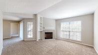 Located in Dallas, TX, this single-floor residence offers a well-designed layout with a variety of functional and stylish features throughout. The living room serves as the centerpiece of the home, showcasing a tiled fireplace flanked by built-in shelving, vaulted ceilings, and multiple windows with blinds that invite generous natural light. Neutral-toned carpet and warm beige walls create a calm, cohesive atmosphere throughout the living areas. The kitchen is efficiently arranged with white shaker cabinetry, granite countertops, a stainless steel sink, and black appliances, including a range, microwave, and refrigerator. Rich wood-look flooring grounds the space with a polished finish. The bedrooms are carpeted and include ceiling fans, ample closet space, and windows for natural light. One bedroom features a generous walk-in closet outfitted with multi-level wire shelving. The bathrooms are well-appointed, with granite vanity tops, white cabinetry, wood-look flooring, and large-format white tile surrounding the tub-shower combinations. An open area connecting the living room and kitchen provides a flexible, airy flow, making this residence a practical and comfortable home in the heart of Dallas.