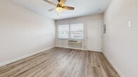 Located at 4949 W Century Blvd in Inglewood, California, this efficiently designed single-floor unit offers a practical and modern layout comprising a living room, kitchen, and bathroom. Throughout the space, light-toned wood-look flooring creates a cohesive and clean aesthetic that ties each area together seamlessly.

The living room serves as the central gathering area, featuring neutral white walls, a ceiling fan with integrated lighting, and a wall-mounted PTAC heating and cooling unit for year-round climate control. White horizontal blinds on the windows allow for natural light while maintaining privacy. An electrical panel is also conveniently accessible within the main living area.

The kitchen is outfitted with stainless steel appliances, including a gas range and an over-the-range microwave, complemented by white cabinetry and light countertops. A window with matching white blinds brings in additional natural light, enhancing the functionality of the space.

The bathroom maintains the same clean, modern design language, finished with wood-look flooring and a glass-enclosed walk-in shower. The all-white palette creates a bright and airy feel.

Overall, this unit offers a streamlined, move-in-ready environment with consistent modern finishes throughout, making it a practical choice in the Inglewood area.