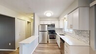 Located at 11201 E 14 Mile Rd in Sterling Heights, Michigan, this thoughtfully updated one-bedroom, one-bathroom unit offers a clean, modern aesthetic throughout. Luxury vinyl plank flooring flows seamlessly across the entire floor plan, complementing the neutral gray and white color palette.

The open-concept kitchen and dining area is a standout feature, showcasing white shaker cabinetry, a mosaic tile backsplash, gleaming white quartz countertops, and a full suite of stainless steel appliances including a refrigerator, range, microwave, and dishwasher. A peninsula counter provides additional prep space and a natural division between the kitchen and dining area.

The living room is generously proportioned, bathed in natural light from large windows and a sliding glass door that opens onto a private balcony with outdoor views. A ceiling fan adds comfort to the space.

The bedroom is a comfortable size, featuring a wide window with views of the surrounding trees and two closets for ample storage. The full bathroom impresses with a dual-sink vanity topped with granite-style countertops, a large mirror, and a tub-shower combination. Additional conveniences include a dedicated laundry area and a hallway connecting all rooms efficiently.