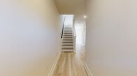 Located at 1801 Guilford Ave in Baltimore, MD, this well-designed three-story home offers 3 bedrooms and 4 bathrooms across three thoughtfully laid-out floors. Light wood-tone flooring runs throughout the home, creating a cohesive, clean aesthetic complemented by neutral walls and crisp white trim.

The main level features an open-concept living, dining, and kitchen area flooded with natural light from multiple windows dressed with classic blinds. The living room includes a ceiling fan and offers a bright, welcoming atmosphere. The kitchen is a standout, boasting two-tone cabinetry — white uppers paired with bold dark lowers — stainless steel appliances, a subway tile backsplash, and a central island with a white quartz countertop and pendant lighting. The dining area sits adjacent, bathed in natural light from surrounding windows.

Each floor is connected by a clean, open staircase with light wood treads and a sleek dark metal railing. The bedrooms are generously lit, with large windows framing views of the surrounding Baltimore neighborhood. The primary bedroom provides a comfortable, private retreat. The four bathrooms are well-appointed, featuring tile flooring, white shaker-style vanities with quartz countertops, and tub-shower combinations with full tile surrounds. The overall ambiance is modern, light, and move-in ready.