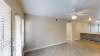 This single-floor, 3-bedroom, 2-bathroom residence provides a well-organized layout designed for comfortable everyday living. The living area features light gray luxury vinyl plank flooring, neutral-toned walls, and a ceiling fan, with a glass door that opens to a private balcony and brings in natural light. The galley-style kitchen is efficiently designed with gray cabinetry, white countertops, a double sink, and stainless steel appliances including a range, microwave, dishwasher, and refrigerator. Each of the three bedrooms is equipped with a ceiling fan and window with blinds allowing ample natural light. The primary bedroom stands out with a curved bay window configuration offering expansive views and two closets with built-in shelving for generous storage. The primary bathroom includes a wide vanity with dual sinks, gray cabinetry, and a large mirror. The secondary bathroom features a tiled tub-shower combo with accent tile detailing, a single vanity with gray cabinetry, and a mirror. Consistent vinyl plank flooring runs throughout the unit, tying together a cohesive, clean aesthetic. Clean white trim and neutral wall tones create a bright, move-in ready environment throughout the entire space.