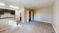 Located at 6775 E Golf Links Rd in Tucson, Arizona, this studio unit offers a well-organized, single-floor layout designed for efficient living. The living area features neutral, warm-toned walls and plush wall-to-wall carpeting that creates a cozy atmosphere, complemented by wood-look flooring near the entryway. A built-in closet with bifold doors provides practical storage directly within the main living space.

The galley-style kitchen is a standout feature, outfitted with dark espresso cabinetry, granite-look countertops, and stainless steel appliances including a range, microwave, and refrigerator. A single-basin sink sits beneath a window that allows natural light to brighten the space. The kitchen transitions seamlessly into the living area via a partial countertop bar that serves as a room divider.

The bathroom is neatly appointed with dark cabinetry topped with a granite-look vanity, a wood-look tile floor, and a full-size soaking tub with shower combination. The overall color palette throughout the unit is cohesive, featuring warm beige tones and white trim that lend the space a clean, understated aesthetic. This unit offers a functional and comfortable layout suited for single-occupancy living in Tucson.