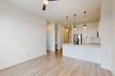 Located at 2825 W 11th St in Houston, TX, this thoughtfully designed one-bedroom, one-bathroom unit offers a clean, modern aesthetic throughout its well-utilized single floor. Light wood-tone flooring runs seamlessly through the space, complementing the crisp white walls and creating a bright, cohesive atmosphere.

The open-concept living, dining, and kitchen area serves as the heart of the home. The kitchen is outfitted with white shaker cabinetry featuring matte black hardware, a white quartz waterfall island with an undermount sink, stainless steel appliances including a French door refrigerator and over-the-range microwave, and a white subway tile backsplash. A trio of pendant lights with brass accents hang above the island, adding warmth and character. Built-in shelving and a small built-in desk nook add functional charm to the living area.

A hallway with paneled white doors connects the main living space to the private quarters. The bedroom is generously sized, offering multiple windows with natural light and outdoor views, plus a ceiling fan. Two closets provide ample storage.

The bathroom is a standout feature, showcasing a dual-sink vanity with a white quartz countertop, matte black fixtures, framed mirrors, and a floor-to-ceiling marble-tiled walk-in shower with a glass enclosure. A dedicated office and in-unit laundry area complete this well-appointed home.