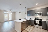 Located at 180 Jackson St NE in Atlanta's vibrant Old Fourth Ward neighborhood, this well-appointed one-bedroom, one-bathroom residence offers a thoughtfully designed single-floor layout. Light wood-tone flooring flows consistently throughout the space, creating a cohesive and modern aesthetic.

The open-concept kitchen and living area forms the heart of the home. The kitchen is outfitted with sleek gray cabinetry, a white quartz peninsula with an undermount sink, stainless steel appliances including a range, microwave, dishwasher, and refrigerator, and a classic subway tile backsplash. Pendant lighting above the peninsula adds a stylish, functional touch. The adjacent living area is bright and airy, featuring a ceiling fan and French doors that open to an outdoor area, flooding the space with natural light.

The bedroom is a comfortable, well-proportioned retreat with a ceiling fan, a window with outdoor views, and access to a dedicated closet. Neutral wall tones throughout contribute to a calm, move-in ready atmosphere.

The bathroom is clean and functional, featuring a vanity with quartz countertop, gray cabinetry, a combination tub and shower, and matching wood-tone flooring. A hallway connects all rooms efficiently, completing this practical and attractive floor plan.