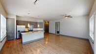 This thoughtfully designed two-bedroom, two-bathroom residence in Spring, Texas, offers a cohesive open-concept layout across a single floor. The kitchen serves as a central hub, showcasing granite-style countertops, a substantial island with pendant lighting, dark wood cabinetry, stainless steel appliances, a tile backsplash, and track lighting overhead. Wood-look flooring flows throughout the main living areas, adding warmth and continuity.

The living room features a ceiling fan, sliding glass doors that open to a private balcony, and large windows that invite natural light. The primary bedroom includes plush carpeting, a bold accent wall, and a window workspace area. Its en-suite bathroom offers a dual-sink vanity with granite countertops, dark cabinetry, a walk-in shower with glass enclosure, and a walk-in closet. The second bedroom is equally well-appointed, with natural light and a warm accent wall. The second bathroom provides a full tub-shower combination and matching vanity finishes. An in-unit washer and dryer area adds convenience, completing this well-equipped residence.