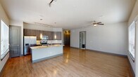 This thoughtfully designed two-bedroom, two-bathroom residence in Spring, Texas, offers a cohesive open-concept layout across a single floor. The kitchen serves as a central hub, showcasing granite-style countertops, a substantial island with pendant lighting, dark wood cabinetry, stainless steel appliances, a tile backsplash, and track lighting overhead. Wood-look flooring flows throughout the main living areas, adding warmth and continuity.

The living room features a ceiling fan, sliding glass doors that open to a private balcony, and large windows that invite natural light. The primary bedroom includes plush carpeting, a bold accent wall, and a window workspace area. Its en-suite bathroom offers a dual-sink vanity with granite countertops, dark cabinetry, a walk-in shower with glass enclosure, and a walk-in closet. The second bedroom is equally well-appointed, with natural light and a warm accent wall. The second bathroom provides a full tub-shower combination and matching vanity finishes. An in-unit washer and dryer area adds convenience, completing this well-equipped residence.
