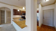 Located at 921 S Orlando Ave in Maitland, Florida, this single-floor residence offers a thoughtfully designed open-concept layout that seamlessly connects the main living areas. The kitchen is a standout feature, showcasing rich dark wood cabinetry, granite countertops, and hardwood flooring. It is fully equipped with stainless steel appliances, including a refrigerator and microwave, complemented by a black range and a double-basin sink. A peninsula with a granite overhang opens to the living and dining areas, making it ideal for entertaining. The living area is generously proportioned, featuring plush neutral carpeting, crown molding, track lighting, and a sliding glass door that invites natural light and outdoor access. The bedroom spaces are equally well-sized, each offering soft carpeting, ceiling fans, and ample natural light through slatted blinds. At least one bedroom includes a walk-in closet, providing excellent storage. The bathroom features warm hardwood-style flooring, a granite-topped vanity with dark wood cabinetry, and a tiled tub-shower combination. Throughout the residence, consistent finishes including crown molding, neutral tones, and quality flooring create a cohesive and comfortable living environment.
