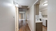 This two-story residence is thoughtfully laid out across two equally sized floors, providing a well-organized and functional living environment. The main level features a living room with dark hardwood-style flooring, exposed beam detailing on the textured ceiling, and a large sliding door dressed with vertical blinds that allow natural light to fill the space. The combined dining and kitchen area offers a galley-style kitchen equipped with white appliances including a range, refrigerator, and dishwasher, complemented by speckled quartz-style countertops, gray cabinetry, and wood-look flooring. A pantry provides additional storage convenience nearby. The dedicated laundry room accommodates a full-size washer and dryer side by side, with a window for natural light. Three carpeted bedrooms offer comfortable, quiet retreats, each with windows fitted with blinds. The three bathrooms are finished consistently, featuring wood-look flooring, speckled countertops, and tub-shower combinations with tile surrounds. One bathroom includes a dual-sink vanity with mirrored medicine cabinets and direct access to a walk-in closet. Five closets throughout the home ensure ample storage. Neutral tones and textured ceilings are consistent throughout, lending a cohesive and clean aesthetic to the entire space.