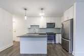 Located at 4981 Bathurst St in North York, Toronto, this well-appointed one-bedroom, one-bathroom unit offers a thoughtfully designed layout across a single floor. The open-concept kitchen and living area serves as the heart of the space, showcasing crisp white shaker cabinetry, a light grey subway tile backsplash, and dark countertops that provide a striking contrast. A central kitchen island offers additional prep and dining space, while pendant lighting adds a modern, polished touch. Stainless steel appliances — including a refrigerator, range, microwave, and dishwasher — complete the kitchen's contemporary feel. Warm hardwood-style flooring runs throughout, lending a cohesive and inviting character to the entire unit. The bedroom is a serene, light-filled retreat with two windows overlooking greenery, offering pleasant outdoor views and a calm ambiance. A wall-mounted heating unit ensures year-round comfort. The bathroom features classic white subway tile surrounding a full soaker tub and shower combination, accented by chrome fixtures for a clean, timeless finish. Overall, the unit's modern finishes, functional layout, and natural light make it a practical and attractive living space in a convenient Toronto neighbourhood.