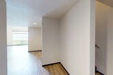 This two-story residence is thoughtfully laid out across two generously sized floors of nearly equal proportion, providing ample space for comfortable living. The main level features a well-appointed kitchen with rich dark wood cabinetry, dark granite countertops, a central island, stainless steel appliances, and warm pendant lighting — all complemented by light hardwood flooring that flows throughout the lower level. The living room connects seamlessly to the kitchen, creating an open, functional common area.

A hallway and staircase connect the two floors, with the upper level featuring a sleek metal railing that overlooks large windows framing tree-lined outdoor views. The upper floor is carpeted and houses the bedrooms, including a notably spacious primary bedroom bathed in natural light through a large picture window with outdoor views. Two closets provide dedicated storage, including a walk-in closet with built-in shelving and hardwood flooring. The dedicated laundry room includes a full-size washer and dryer. Throughout, the interior maintains a clean, modern aesthetic with neutral white walls, recessed lighting, and consistent wood-look flooring on the main level.