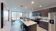 Located at 35 E Central Pkwy in the heart of Cincinnati, Ohio, this modern urban residence offers a thoughtfully designed open-concept layout that seamlessly connects the kitchen, dining, and living areas. Floor-to-ceiling windows flood the living room with natural light and frame sweeping panoramic views of the downtown Cincinnati skyline, creating a striking focal point throughout the space.

The kitchen is outfitted with dark espresso cabinetry, crisp white countertops, a classic subway tile backsplash, and a full suite of stainless steel appliances including a refrigerator with ice maker, electric range, and built-in microwave. A large center island with bar seating provides additional prep space and casual dining.

The bedroom continues the floor-to-ceiling window theme, capturing expansive city views alongside exposed concrete architectural columns that lend an industrial-modern character to the room. The bathroom features a clean, contemporary design with a undermount sink, neutral stone-tone countertops, and a large vanity mirror.

Additional highlights include a dedicated in-unit laundry closet with a full-size washer/dryer, recessed lighting throughout, and a versatile secondary room suitable for a home office or media space. The overall ambiance is sleek, light-filled, and polished, reflecting the vibrancy of its downtown Cincinnati location.