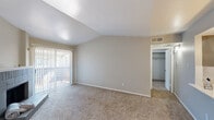 This single-story residence located at 8300 Arabella Ct in Fort Worth, Texas, offers a well-organized layout designed for comfortable everyday living. The entryway welcomes residents through a solid paneled front door, transitioning from a small section of dark hardwood-style flooring into soft, neutral-toned carpeting that extends throughout the main living areas and bedrooms.

The living room is a spacious, open area featuring vaulted ceilings that lend a sense of airiness to the space. Neutral beige walls complement the light carpet, while a sliding glass door provides direct access to a private outdoor patio, allowing natural light to filter into the room. Adjacent to the living area is a walk-in closet, adding practical storage convenience.

The kitchen is a galley-style space finished with gray cabinetry, white countertops, dark hardwood-style flooring, and stainless steel appliances including a refrigerator, microwave, and range. Track lighting overhead ensures the kitchen is well-illuminated. A pass-through opening connects the kitchen to the main living area, enhancing the open feel of the floor plan.

The bedrooms are carpeted and feature clean, neutral walls with natural light provided by standard windows. The bathroom includes a gray vanity with white countertop, a framed mirror, and a textured wall finish, offering a clean and functional design throughout.