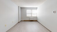 Located at 2420 Oneida St in Utica, New York, Unit 404 is a well-organized one-bedroom, one-bathroom residence situated on a single floor. The layout makes efficient use of its space, seamlessly connecting a living area, kitchen, bedroom, and bathroom in a straightforward, functional arrangement.

The living area features light-toned luxury vinyl flooring that continues throughout the unit, neutral gray walls, and a textured ceiling. Natural light filters in through a window fitted with horizontal blinds, creating a calm and inviting atmosphere.

The bedroom is a comfortable, private space illuminated by a window with blinds and equipped with baseboard heating. A set of full-width wooden sliding closet doors provides generous storage, complemented by a warm wood-toned entry door that connects to the rest of the unit.

The kitchen includes wood-finish cabinetry offering ample storage and workspace. The bathroom is notably accessible, featuring a full bathtub and shower combination equipped with stainless steel grab bars on multiple walls, a handheld showerhead, and a vanity with cabinet storage below — all finished with clean white surrounds and the same durable flooring found throughout the unit.

Overall, this residence presents a clean, practical, and accessibility-conscious living environment in the heart of Utica, NY.
