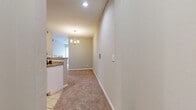 This single-story residence offers a thoughtfully designed layout comprising two bedrooms, three bathrooms, a kitchen, living room, hallway, and entrance. The interior is finished with neutral warm-toned walls and plush carpeting throughout the main living and bedroom areas, while tile flooring is utilized in the kitchen and bathrooms for practicality.

The kitchen is well-equipped with stainless steel appliances, including a refrigerator, range, microwave, and dishwasher. White cabinetry pairs with granite countertops and a subway tile backsplash, creating a clean, modern aesthetic. A peninsula provides additional counter space and opens toward the hallway and living area.

The living room is carpeted and anchored by a tile-surround fireplace with a white mantel, complemented by a window that allows natural light to filter in. A pendant chandelier in the hallway adds a decorative touch to the transition between spaces.

The primary bedroom features a ceiling fan, a window for natural light, and direct access to an en-suite bathroom with white cabinetry and a walk-in closet fitted with organized wire shelving systems. The secondary bedroom similarly offers carpeting, a ceiling fan, and a window. The bathrooms are finished with tile flooring and include tub-shower combinations.