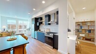 This thoughtfully designed one-bedroom, one-bathroom residence offers a smart, efficient layout across a single floor. The open-concept kitchen and living area serves as the heart of the home, where a sleek, modern kitchen takes center stage. Outfitted with navy and dark cabinetry, a white square-tile backsplash, stainless steel appliances including a gas range, dishwasher, and full-size refrigerator, and a stainless steel wall-mounted range hood, the kitchen is both functional and visually striking. Light wood flooring extends throughout, lending warmth and continuity to the space. The living area is bathed in natural light from large floor-to-ceiling windows that frame views of the surrounding cityscape, creating an airy, open ambiance. The bedroom is a serene retreat, featuring a wide horizontal window with outdoor views, a ceiling fan, and warm wood flooring. The bathroom is clean and contemporary, with a sleek vanity and in-unit stacked washer and dryer conveniently located nearby. A dedicated closet and an additional nook with open shelving provide practical storage solutions. Recessed lighting throughout ensures a bright, modern feel in every corner of this well-appointed residence.