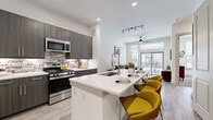 Located in Houston's vibrant 77007 neighborhood, this modern single-story residence at 3030 Summer St offers a thoughtfully designed open-concept layout that seamlessly connects the kitchen, dining, and living areas. The kitchen is a standout feature, showcasing dark wood cabinetry, a textured stone tile backsplash, stainless steel appliances, and a generous quartz-topped island with an integrated sink and bar seating — ideal for both cooking and casual dining. Light wood-style flooring flows throughout the main living areas, complementing the clean white walls and recessed lighting. The living room is bathed in natural light from expansive floor-to-ceiling sliding glass doors that open to a private balcony with outdoor views, creating a seamless indoor-outdoor connection. A ceiling fan adds practical comfort to the space. The bedroom is a serene retreat, featuring plush carpeting, large windows that invite natural light, and ample closet space. The bathroom is finished with large-format grey tile, dark wood vanity cabinetry, quartz countertops, and a full soaking tub with shower. A stacked in-unit laundry is also included, adding everyday convenience to this well-appointed Houston residence.
