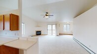 This single-floor residence offers a practical and comfortable layout designed for ease of living. The main living area is immediately welcoming, featuring vaulted ceilings accented by a ceiling fan and a tile-surround fireplace as a central focal point. Sliding glass doors lead directly to an outdoor deck, filling the space with natural light and providing convenient exterior access. Multiple windows throughout reinforce the bright, airy atmosphere.

The kitchen is efficiently designed in a U-shaped configuration, outfitted with warm oak cabinetry offering generous storage, white appliances including a refrigerator, electric range, built-in microwave, and dishwasher, complemented by tile flooring and a window above the sink. A half-wall separates the kitchen from the living area, maintaining an open connection between the two spaces.

The bedrooms are carpeted and well-proportioned, each equipped with ceiling fans. One bedroom benefits from dual windows providing views of the surrounding landscape, while another includes a walk-in closet with tile flooring. Baseboard heating is present throughout the unit.

The bathroom is notably functional, incorporating a stacked washer and dryer unit alongside a vanity with oak cabinetry, a wide mirror, and tile flooring, consolidating laundry and bath facilities efficiently within one room.