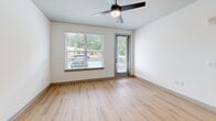 Located in Acworth, GA, this well-designed 1-bedroom, 1-bathroom unit offers a comfortable and modern living experience across a single floor. The open-concept kitchen and living area serves as the heart of the home, showcasing a striking two-tone kitchen with crisp white upper cabinets and bold navy lower cabinets accented by gold hardware. A large white center island with pendant lighting provides both additional prep space and a casual dining option. Stainless steel appliances, a subway tile backsplash, and a matte black faucet complete the kitchen's contemporary aesthetic. Light hardwood-style flooring flows throughout the main living areas, enhancing the bright, airy atmosphere created by recessed lighting and natural light. The living room features a ceiling fan and a glass-panel door leading to an outdoor area, with large windows offering views of the surrounding greenery. The bedroom is a comfortable retreat with plush carpeting, a ceiling fan, and a window that invites in natural light. The bathroom is elegantly appointed with a navy vanity with gold hardware, a glass-enclosed walk-in shower with large-format tile, and direct access to a dedicated walk-in closet, adding a practical touch of luxury to the space.