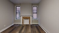 Located in Pittsburgh's Bloomfield neighborhood, this thoughtfully renovated single-floor unit at 332 S Mathilda Street combines classic architectural character with modern updates throughout. Rich hardwood flooring runs through the main living areas, complementing the neutral gray walls and crisp white trim that define the interior palette.

The living room serves as a standout centerpiece, featuring a decorative fireplace with an ornate mosaic surround flanked by two tall windows that frame views of the surrounding brick architecture. A sliding glass door opens to a private wooden deck, offering a comfortable outdoor extension of the living space.

The kitchen is well-appointed with white shaker cabinetry, granite countertops, and a full suite of stainless steel appliances including a gas range, dishwasher, and refrigerator. The layout provides efficient workspace and connects seamlessly to the main entry and an adjacent laundry area.

Multiple bedrooms offer flexible living arrangements, each finished with hardwood or wood-look flooring, baseboard heating, and windows that bring in natural light. The bathroom features marble-style tile flooring, a white vanity, and clean, modern fixtures throughout.

Baseboard heating is present throughout the unit, ensuring year-round comfort. The overall design reflects a careful balance of updated finishes and timeless details.
