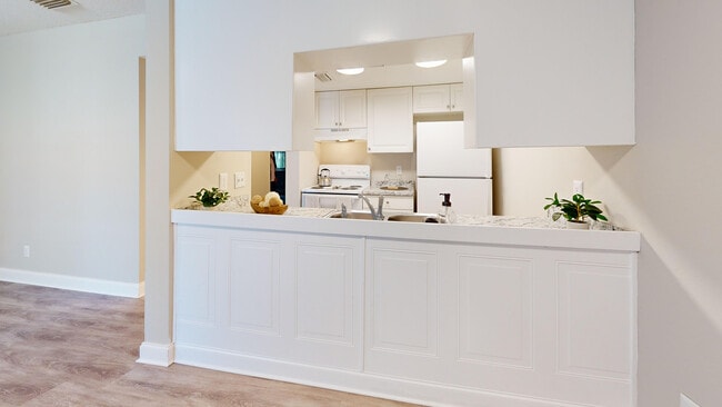 Cocina luminosa y moderna con encimera de mármol, gabinetes blancos y electrodomésticos elegantes perfectos para la creatividad culinaria. - Chateau of Tampa