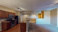 This single-floor residence offers a well-designed open-concept layout that seamlessly connects the kitchen, dining, and living areas. The kitchen is a standout feature, equipped with stainless steel appliances including a gas range, built-in microwave, and refrigerator, all complemented by rich dark wood cabinetry and granite countertops. A generous breakfast bar with a built-in sink provides additional prep space and casual seating. Track lighting and a pendant chandelier illuminate the kitchen and adjoining dining area, while hardwood-style flooring adds warmth underfoot. The living area transitions to plush carpeting and is anchored by a ceiling fan, with access to a private exterior door that invites natural light into the space. A decorative arched niche adds a charming architectural detail to the main living area. The bedrooms are carpeted and generously sized, each featuring ceiling fans and dual closets for ample storage. Both bathrooms are finished with granite-top vanities, tile flooring, and full tub-shower combinations. Neutral warm tones carry throughout the entire residence, creating a cohesive and inviting ambiance from room to room.
