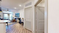This thoughtfully designed one-bedroom, one-bathroom residence delivers a complete and functional layout across a single floor. Light wood-style flooring flows through the main living areas, creating a warm, cohesive aesthetic throughout. The open-concept kitchen is a standout feature, boasting crisp white shaker cabinetry extending to the ceiling, a classic subway tile backsplash, quartz countertops, a stainless steel farmhouse sink, and a full suite of stainless steel appliances including a range, microwave, and refrigerator. A peninsula provides additional prep space and casual seating. The living room is bright and inviting, featuring a ceiling fan, recessed lighting, and French doors that open to a private balcony, filling the space with natural light and outdoor views. The bedroom is a comfortable retreat with plush carpeting, a window with blinds, and a dedicated closet. The bathroom is finished in light-toned tile throughout, offering a tub-shower combination with tile surround and a clean white vanity. In-unit laundry with a full-size washer and dryer adds everyday convenience. The unit also includes a dedicated hallway with HVAC access and well-organized storage, rounding out a practical and polished living experience.