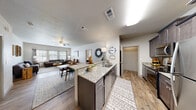 This single-floor residence offers a thoughtfully designed open-concept layout that seamlessly connects the kitchen, dining, and living areas. The kitchen is a functional centerpiece, featuring dark espresso cabinetry, granite countertops, a large island with a built-in sink, and a full suite of stainless steel Whirlpool appliances including a refrigerator, range, microwave, and dishwasher. Light wood-style flooring runs throughout the main living areas, contributing to a bright and cohesive aesthetic.

The living room is generously proportioned, with multiple windows that invite natural light and a ceiling fan for added comfort. A dedicated flex room, ideal for use as a home office or study, is outfitted with plush carpet and a window. The bedroom continues the carpet flooring and includes a ceiling fan and a window with blinds. The full bathroom features matching dark cabinetry with a granite vanity, wood-style tile flooring, and a tiled shower-tub combination.

Additional highlights include a dedicated in-unit laundry closet with a stacked washer and dryer, and a walk-in pantry or closet accessible from the kitchen hallway. Clean white walls and neutral finishes throughout create a versatile, move-in-ready environment.