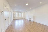 Located on Chemin de la Côte-Saint-Luc in Montréal, this well-appointed 2-bedroom, 1-bathroom unit offers a thoughtfully designed single-floor layout with a clean, modern aesthetic throughout. The spacious living room immediately impresses with its light-toned hardwood flooring, recessed pot lighting, and a charming decorative fireplace that serves as a focal point. A triple window along one wall invites an abundance of natural light, creating a bright and airy atmosphere. The generous hallway connects all rooms seamlessly, offering a sense of openness and flow across the unit. The kitchen is well-equipped with sleek, high-gloss white cabinetry, white quartz countertops, stainless steel appliances including a fridge and electric range, and a window above the sink providing natural light. The primary bedroom is a comfortable, well-sized retreat featuring hardwood floors, a baseboard heater, and a window with an outdoor view. A second bedroom includes a sliding closet and direct access to the hallway. The bathroom is finished in crisp white tiling and features a soaker tub with a glass shower enclosure, a white vanity, and a frosted window. Fresh white walls and consistent hardwood flooring throughout lend the entire unit a cohesive, move-in-ready feel.