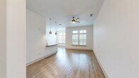 Located at 112 Hera Way in Myrtle Beach, SC, this thoughtfully designed one-bedroom, one-bathroom residence offers a clean, modern aesthetic throughout its single-floor layout. The open-concept living and kitchen area is anchored by warm wood-look flooring, crisp white walls, and abundant natural light streaming through large windows with transom panels. A brass ceiling fan adds a stylish touch to the spacious living room. The galley-style kitchen is well-equipped with stainless steel appliances, including a range, microwave, and refrigerator, complemented by granite countertops, a herringbone tile backsplash, a deep undermount sink, and ample grey shaker cabinetry. Pendant lighting over the breakfast bar ties the kitchen to the living space seamlessly. The bedroom features plush carpet flooring, a ceiling fan, wide windows offering outdoor views, and a dedicated closet. The bathroom is finished with white subway tile in the tub-shower surround, wood-look flooring, and brushed nickel fixtures. A dedicated laundry room with in-unit washer and built-in shelving adds everyday convenience. A hallway connects all areas efficiently, rounding out this well-planned and move-in-ready residence.