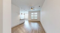 Located at 112 Hera Way in Myrtle Beach, SC, this thoughtfully designed one-bedroom, one-bathroom residence offers a clean, modern aesthetic throughout its single-floor layout. The open-concept living and kitchen area is anchored by warm wood-look flooring, crisp white walls, and abundant natural light streaming through large windows with transom panels. A brass ceiling fan adds a stylish touch to the spacious living room. The galley-style kitchen is well-equipped with stainless steel appliances, including a range, microwave, and refrigerator, complemented by granite countertops, a herringbone tile backsplash, a deep undermount sink, and ample grey shaker cabinetry. Pendant lighting over the breakfast bar ties the kitchen to the living space seamlessly. The bedroom features plush carpet flooring, a ceiling fan, wide windows offering outdoor views, and a dedicated closet. The bathroom is finished with white subway tile in the tub-shower surround, wood-look flooring, and brushed nickel fixtures. A dedicated laundry room with in-unit washer and built-in shelving adds everyday convenience. A hallway connects all areas efficiently, rounding out this well-planned and move-in-ready residence.
