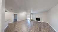 Located at 409 E William Cannon Dr in Austin, TX, this single-story 2-bedroom, 1-bathroom home offers a well-designed layout across a comfortable, efficiently arranged floor plan. Wood-look flooring runs consistently throughout the home, complementing the neutral, warm-toned walls found in every room.

The open kitchen and living area serves as the heart of the home. The kitchen is thoughtfully updated with grey shaker-style cabinetry, granite-look countertops, a subway tile backsplash, a double-basin stainless steel sink, and black appliances including a refrigerator and electric range. A peninsula provides additional counter space and casual seating. The living room features a tiled fireplace as a standout focal point, along with a window that brings in natural light.

Both bedrooms are well-proportioned, each equipped with a ceiling fan and windows fitted with blinds. The primary bedroom includes access to a dedicated walk-in closet with dual hanging rods for ample storage. The bathroom is cleanly finished with a tiled tub-surround shower, wood-look flooring, and a granite-topped vanity. A textured ceiling is consistent throughout the home. The property also includes an outdoor patio area visible from the layout, offering additional exterior space.