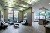 Located at 7 Summerland Terrace in Toronto's Etobicoke neighbourhood, this elegantly designed single-floor amenity space offers a refined and welcoming environment with a cohesive modern aesthetic throughout. Light hardwood flooring runs continuously across the space, complemented by warm taupe and grey tones on the walls that create a calm, sophisticated atmosphere.

The main corridor doubles as a gallery-style walkway, lined with large-scale curated artwork that sets the tone upon entry. A reception area features a concrete console table, pendant lighting, and a full-length mirror, establishing a polished first impression. The lounge area is anchored by a sleek built-in fireplace with a wall-mounted television above, flanked by contemporary seating and decorative sculptures — ideal for relaxed gatherings.

A bright social lounge area features soaring ceilings with exposed beam detailing and dramatic floor-to-ceiling windows that frame lush, verdant outdoor views and fill the space with natural light. Comfortable seating arrangements throughout encourage both conversation and quiet relaxation. A bar-height counter area with stylish seating sits beside a full-height glazed window wall overlooking a landscaped courtyard, providing an ideal spot for casual meetings. Access to an outdoor terrace further extends the usable space into the surrounding greenery.