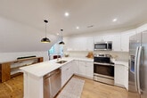 Located at 1 Pleasant St, Unit 307 in Cohasset, MA, this two-bedroom, one-bathroom unit offers a well-designed layout with a coastal-inspired aesthetic and quality finishes throughout. Warm hardwood floors flow seamlessly across the entire space, complementing the crisp white walls and trim that create a bright, airy atmosphere.

The open-concept kitchen and living area serves as the heart of the unit. The kitchen is outfitted with white shaker-style cabinetry, stainless steel appliances, quartz countertops, and a large waterfall island with a brass-toned sink and pendant lighting above — ideal for both cooking and casual dining. The adjoining living area features recessed lighting, a window offering tree-lined views, and a comfortable, welcoming ambiance.

The primary bedroom is a well-proportioned retreat with natural light streaming through a double-paned window and a closet. The second bedroom features a vaulted roofline with a charming angled ceiling, a window with greenery views, and a built-in nook. The full bathroom is finished in clean white tile with a soaking tub, a white vanity, and a window that brings in natural light. Throughout the unit, the architectural details — from the vaulted ceilings to the refined trim work — reflect a thoughtfully designed and move-in-ready space.